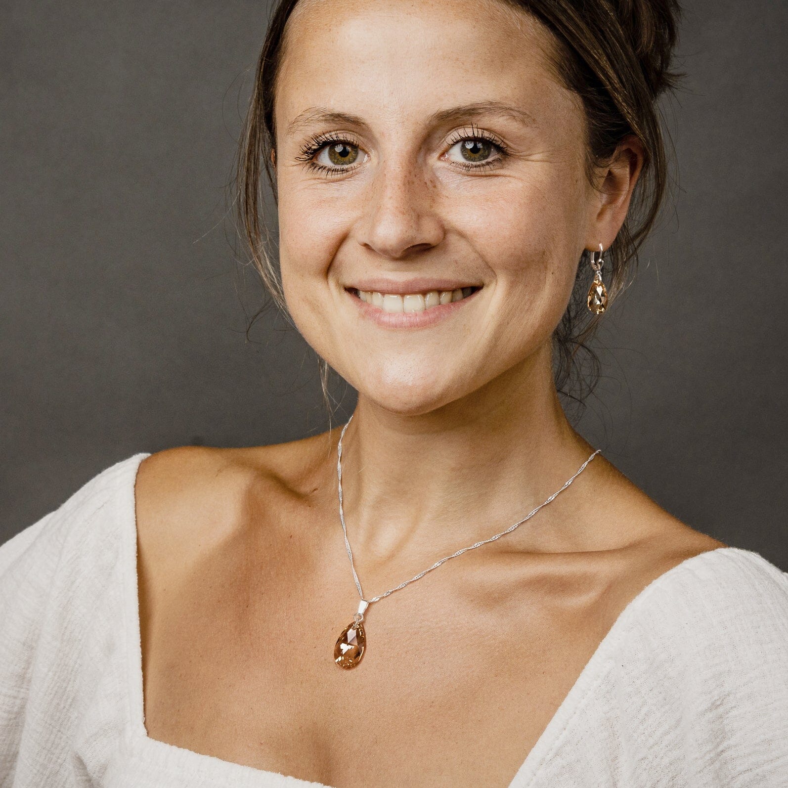 In der Farbe Golden Shadow funkelnder Pear-shaped Tropfen Kristall mit 925 Silberkette am Hals getragen und passende Ohrhänger.