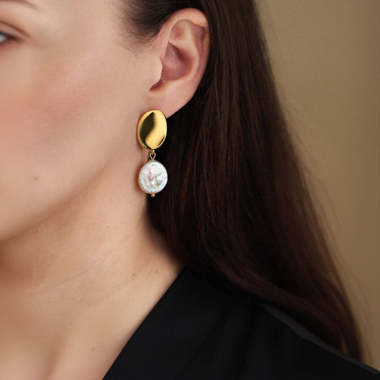 Goldfarbene Edelstahl Ohrringe mit hängender Süßwasser-Münzperle am Ohr getragen, Ansicht Detail